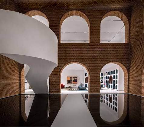 Brick arches and a sculptural stair in a contemporary atrium
