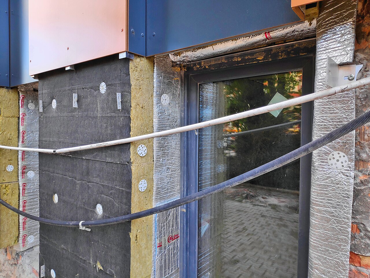 Thermal insulation retrofit works on a department store building in Bytom, Poland, using mineral wool and an aluminium composite mat