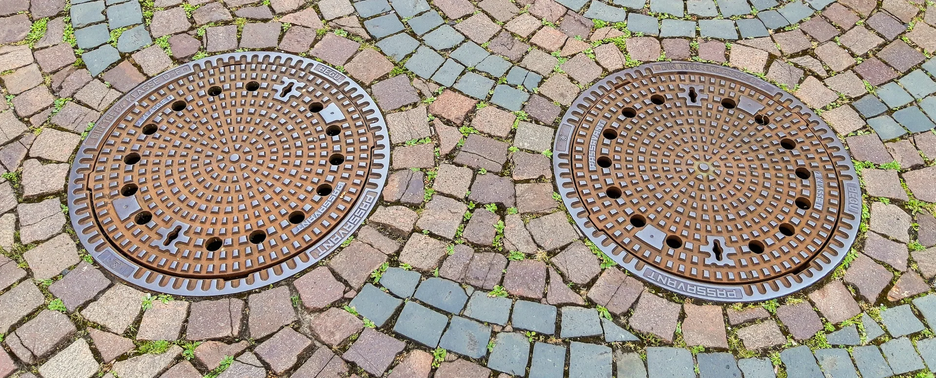 Two round access covers on inspection chambers set into the ground