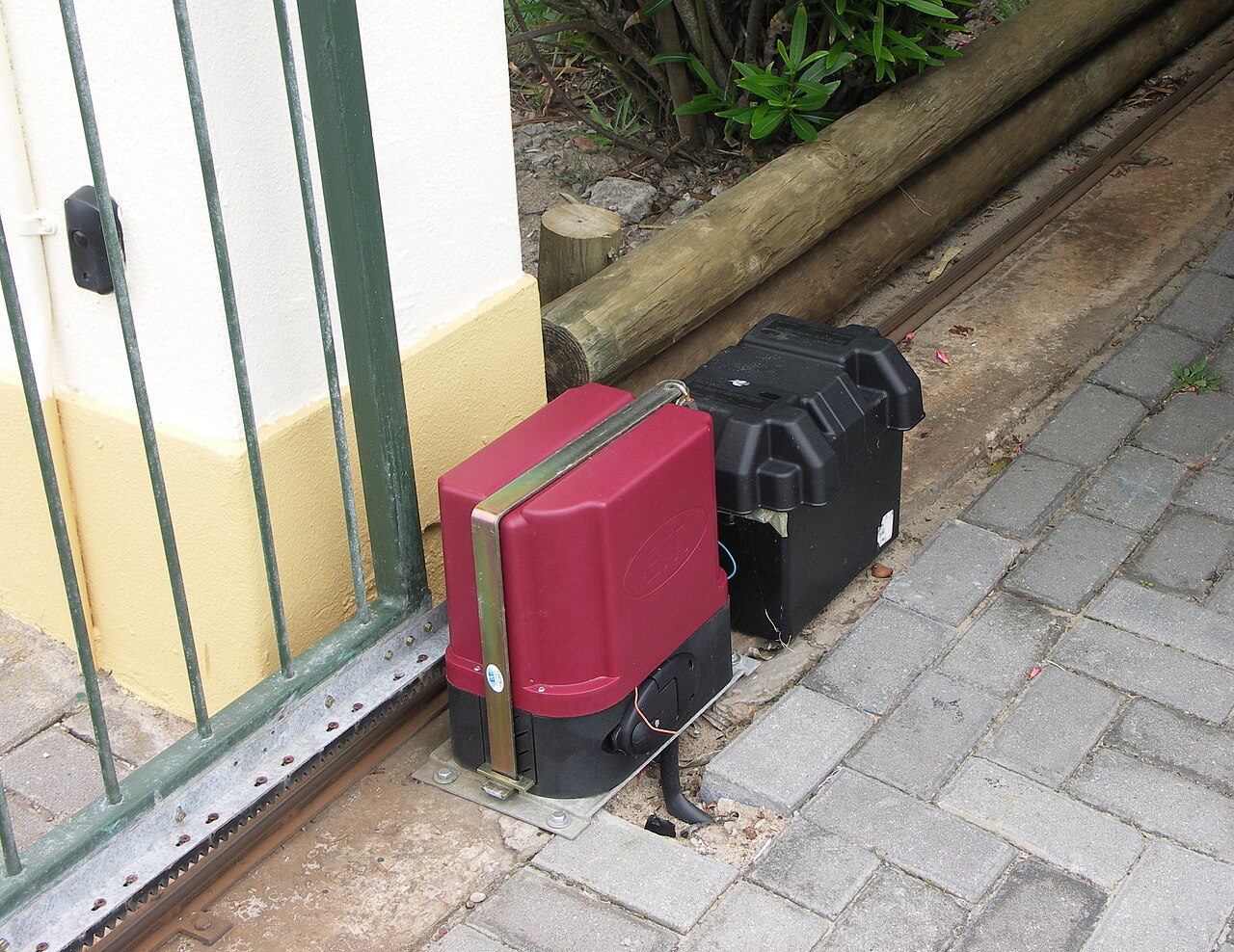 A sliding gate with its electric motor, backup battery, track, gear rack and infra-red obstacle sensor