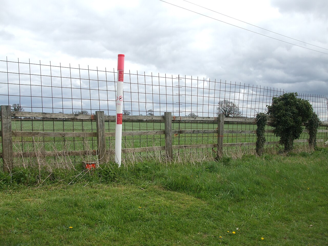 A mesh fence beside an above-ground gas pipe