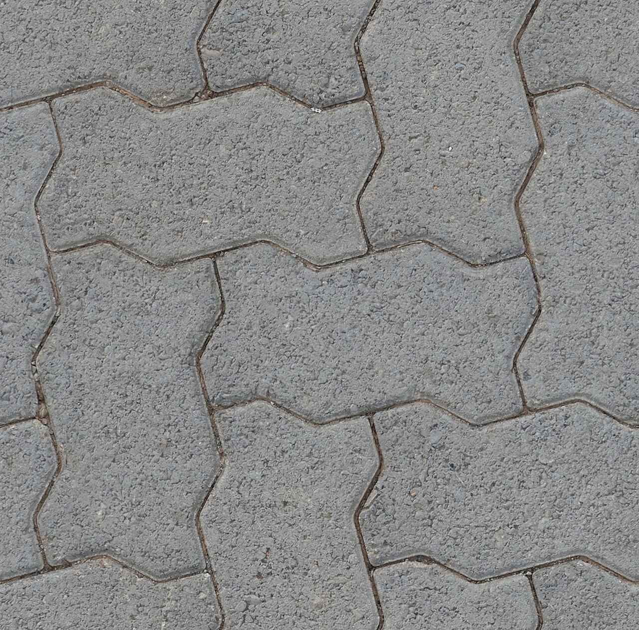 Grey interlocking shaped paving blocks laid in herringbone
