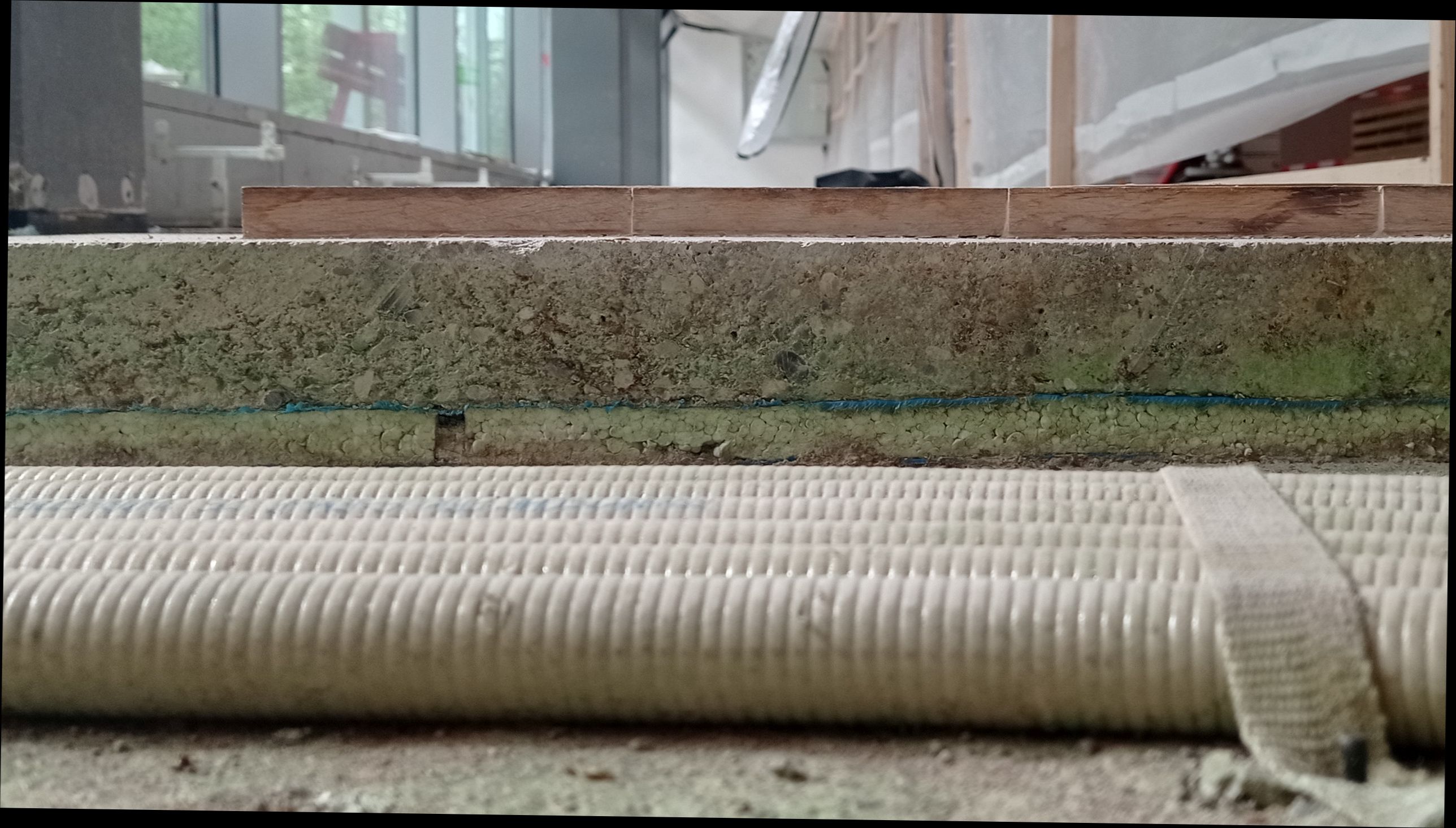 A floating screed cut open, showing the insulation layer, membrane, screed and floor covering