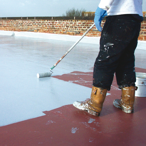 A worker rolling a liquid-applied coating across a flat roof beside an area already covered