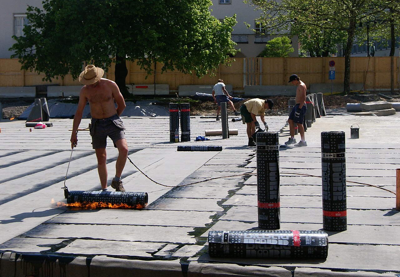 A worker torching a bitumen membrane onto a substrate