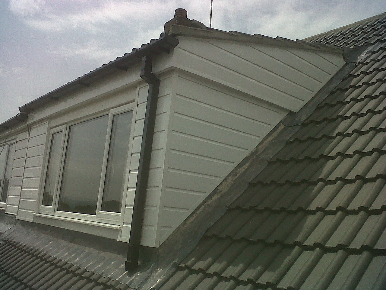 A house roof re-covered with concrete tiles around a dormer
