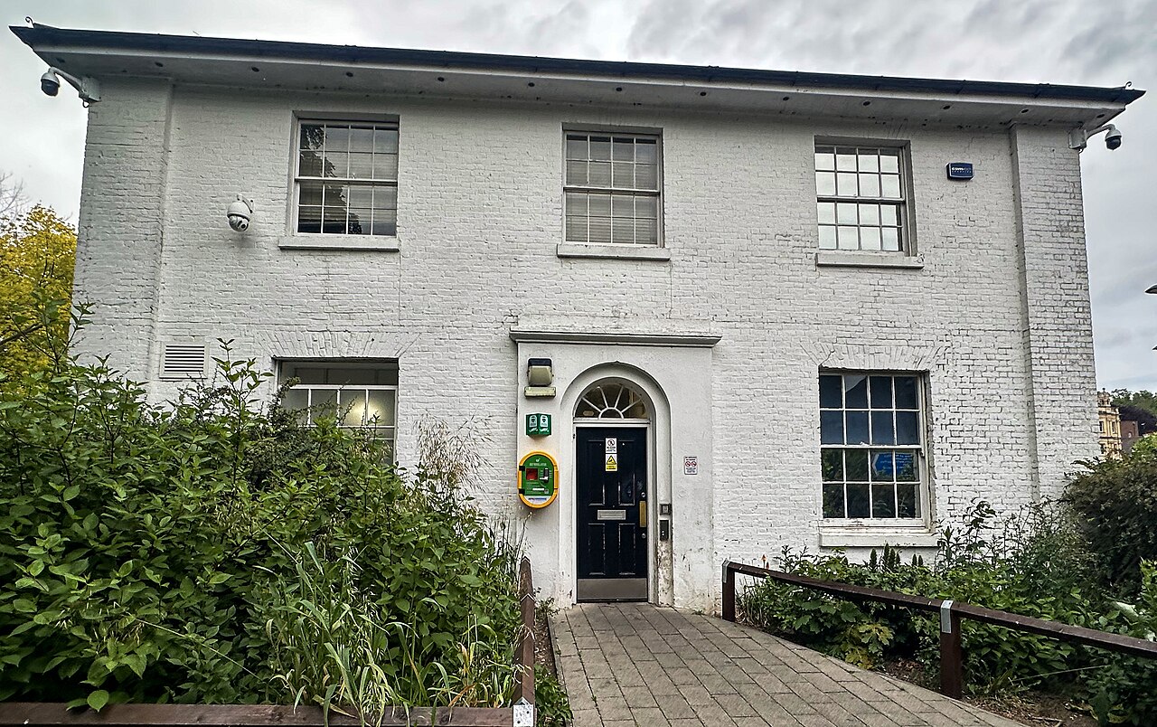 A Georgian-style painted brick building with a fanlight doorway, sash windows and a hipped roof in Chatham, Kent