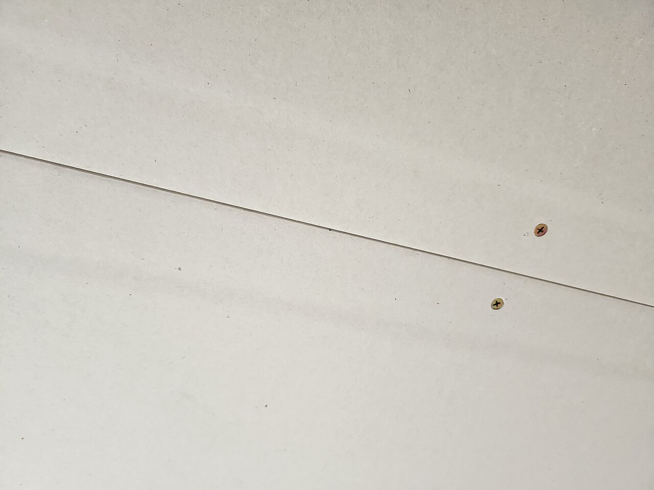 Plasterboard fixed to a wall with screws along the tapered edges of the boards