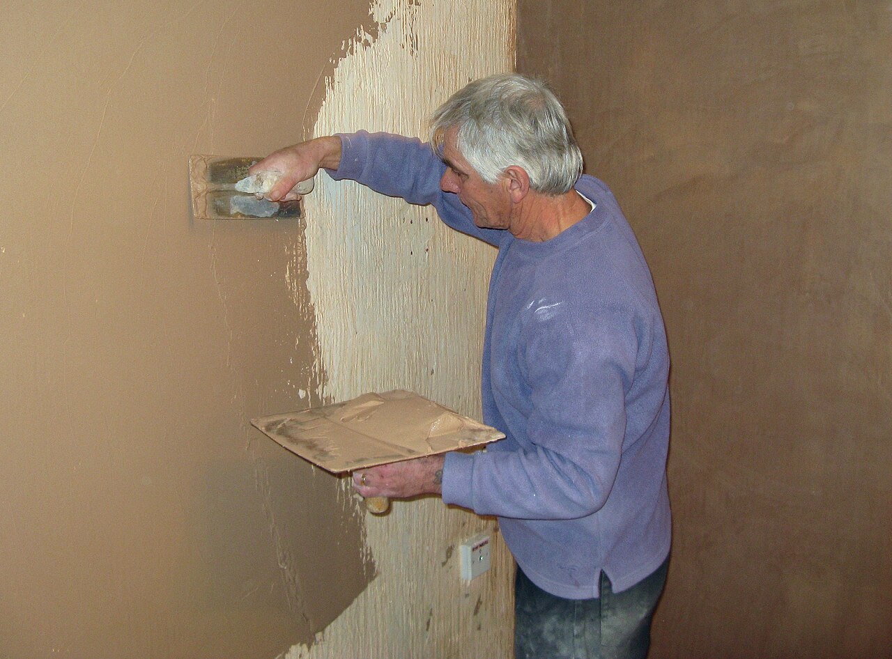 A plasterer plastering a wall in a house in Yate, South Gloucestershire