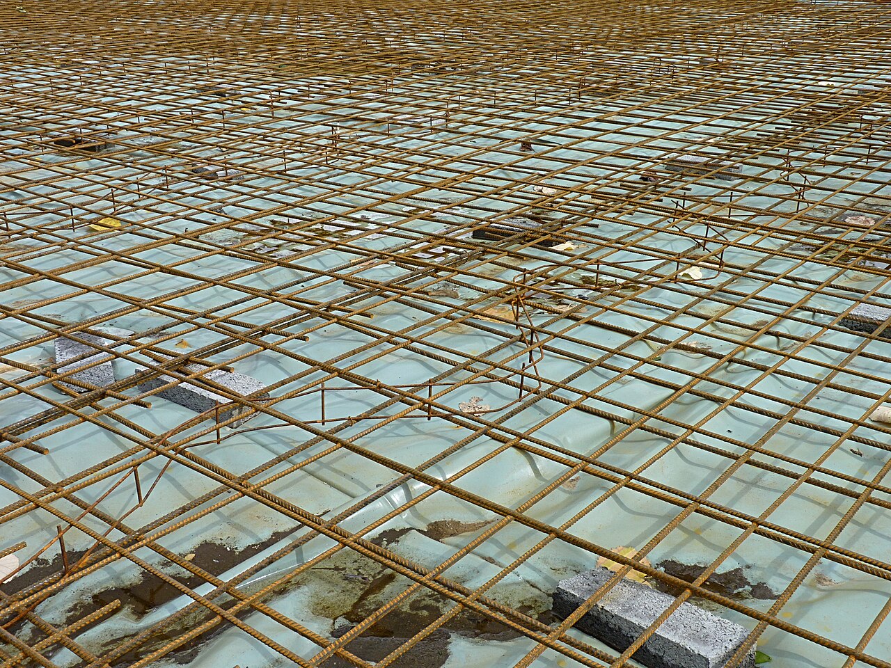 Steel reinforcement for a concrete slab set out on a plastic sheet, photographed in Belgium