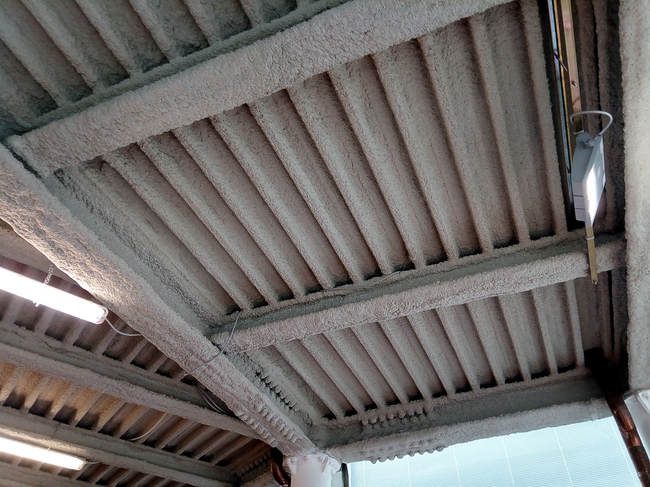 Steel beams coated with a sprayed gypsum and vermiculite fire protection layer