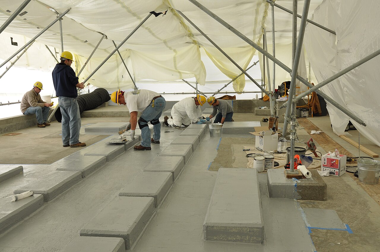 Workers applying an epoxy coating to the concrete floor of an industrial building