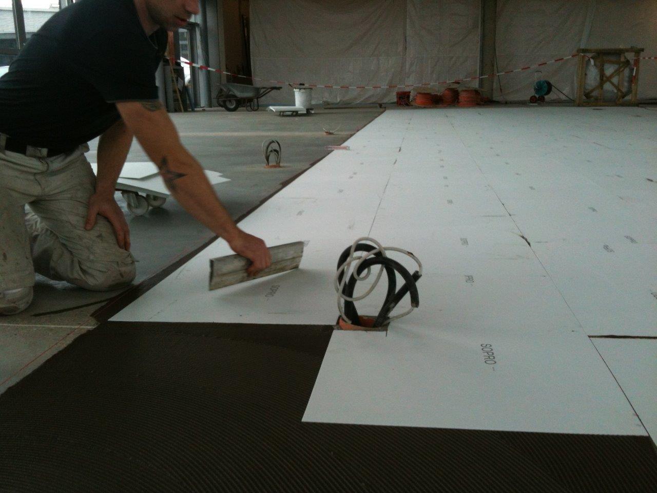 Decoupling boards being bonded to a floor with tile adhesive before tiling