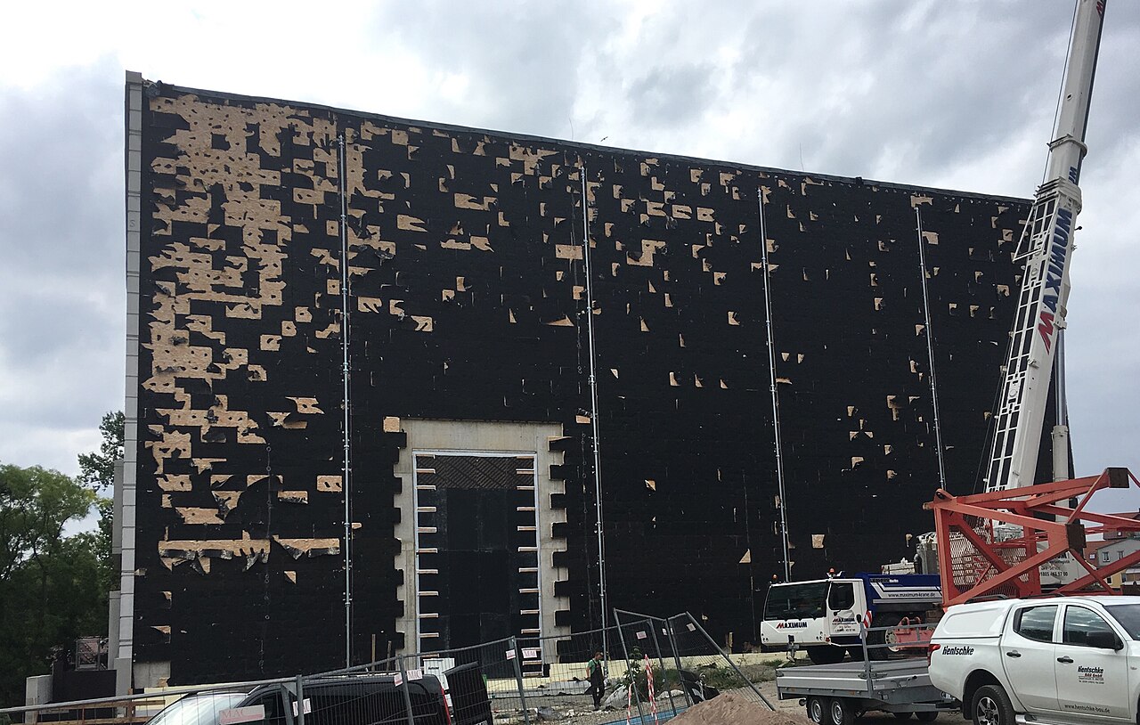 Mineral wool insulation with a black textile covering, partly blown away by a storm, on the facade of the new Bauhaus Museum in Weimar during construction