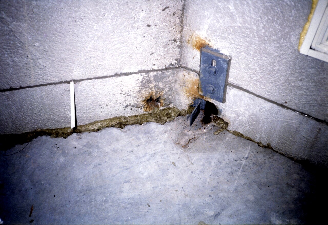 Precast concrete facade panels seen from inside, with fixings, sealed panel joints and rock wool packing at an unfinished firestop