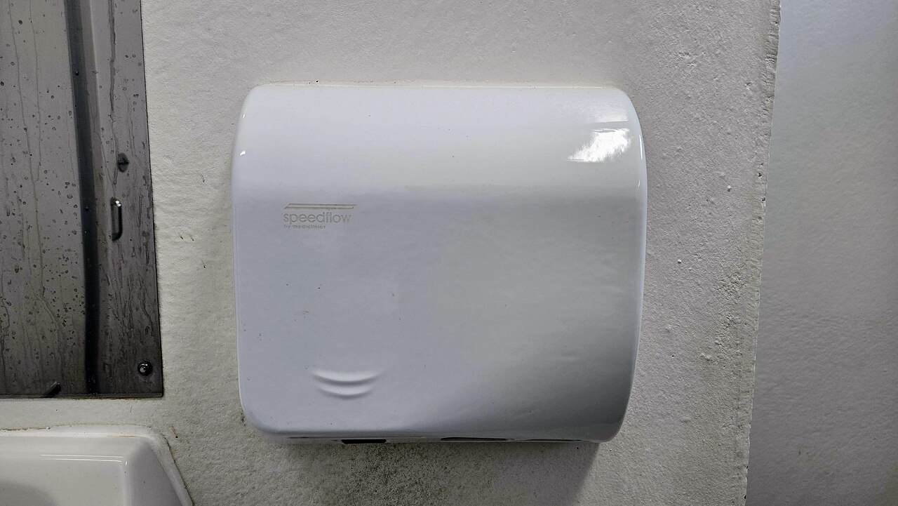 A wall-mounted hand dryer in a washroom