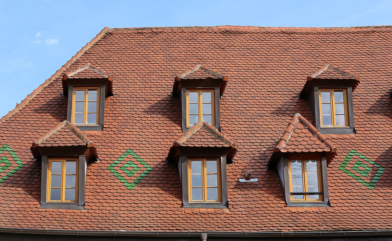 Hipped dormers set in a roof covered with plain tiles on a historic building in Ribeauvillé, France