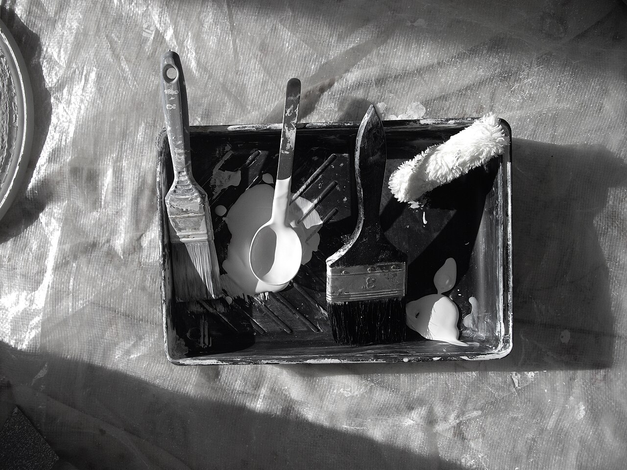 A paint tray, brush and roller with paint, photographed while decorating a house