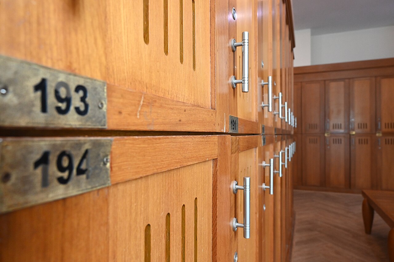 Rows of numbered wooden lockers with metal handles and ventilation slots in a changing room