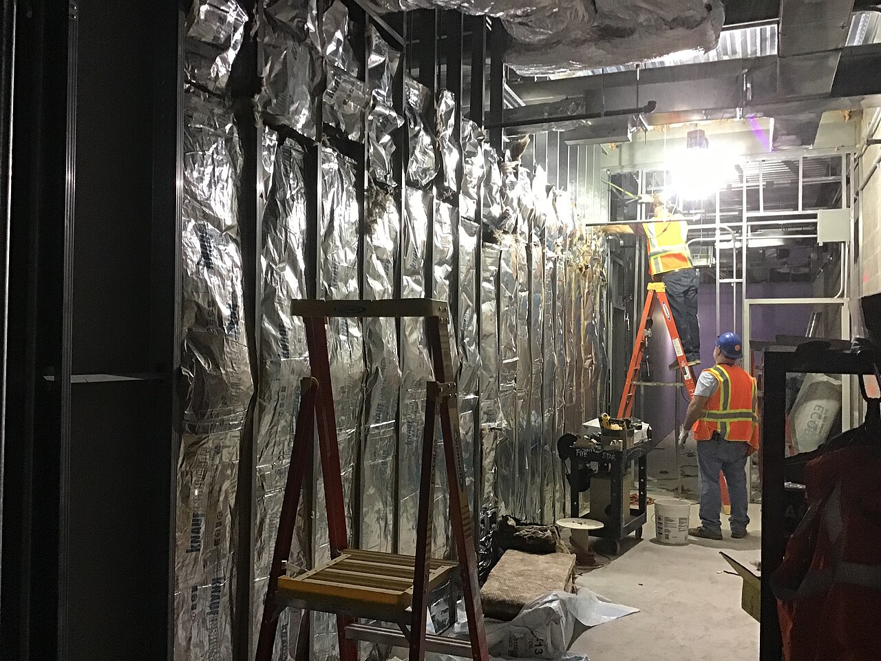 Carpenters fixing gypsum boards to walls in a back-of-house area of a rail concourse under construction