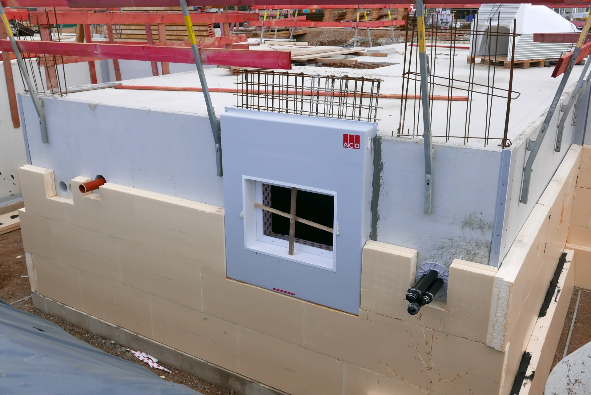 Perimeter insulation on a basement wall around a multi-service entry and a basement window