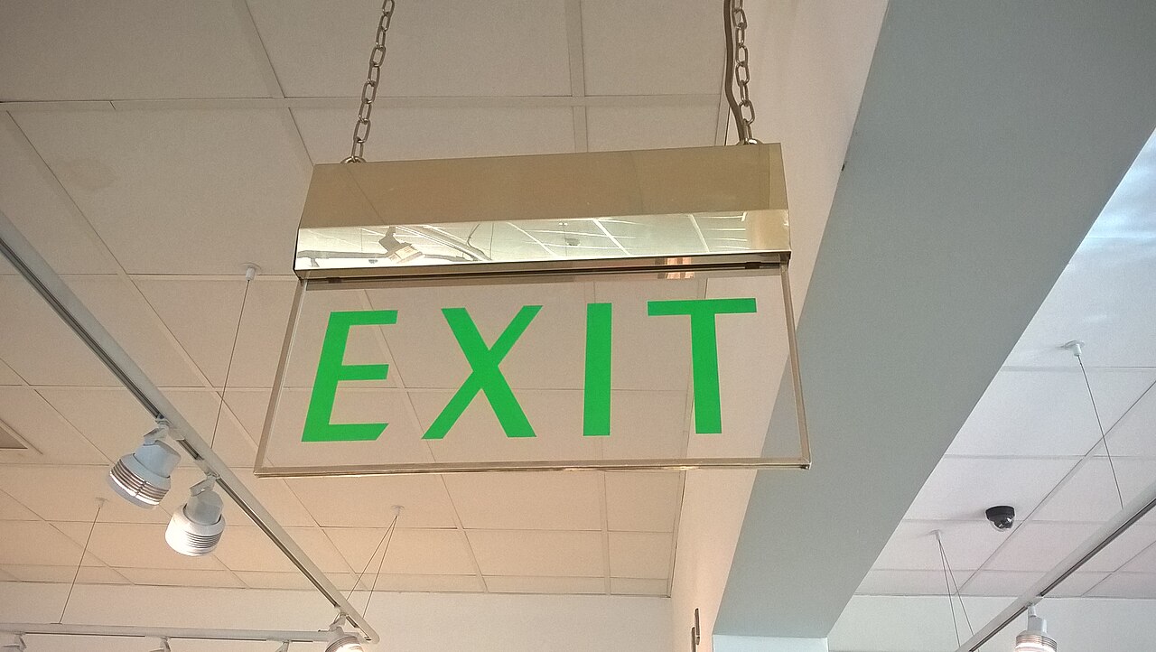 An older text-only fire exit sign in a UK building