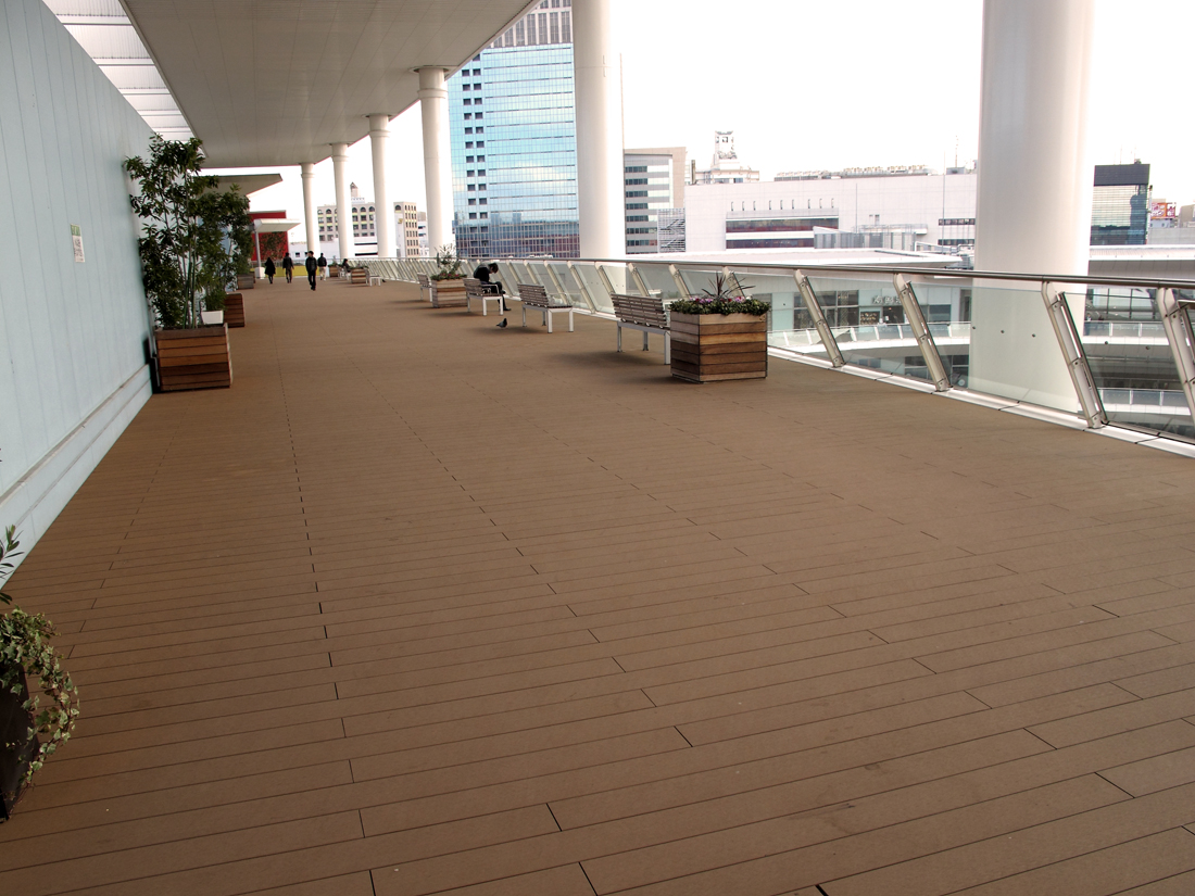 Composite deck boards running across an open public promenade, with their joints and long board lengths visible