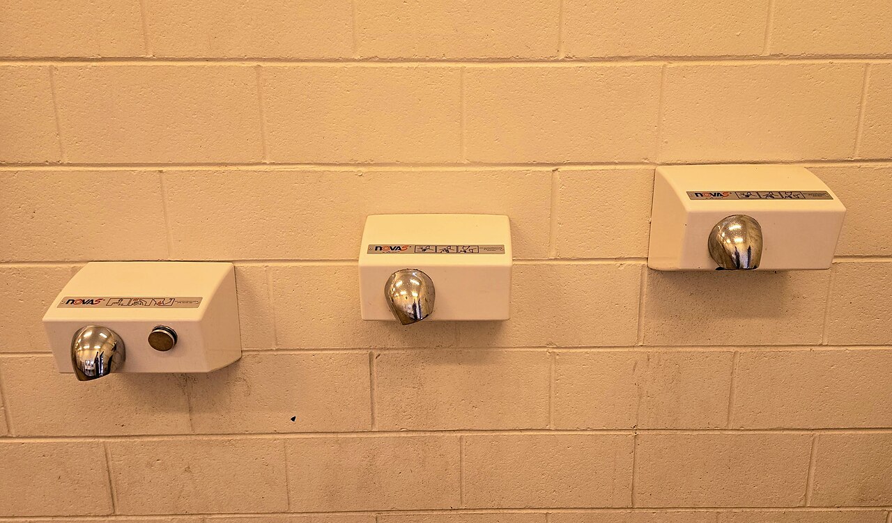 Three hand dryers mounted on a washroom wall