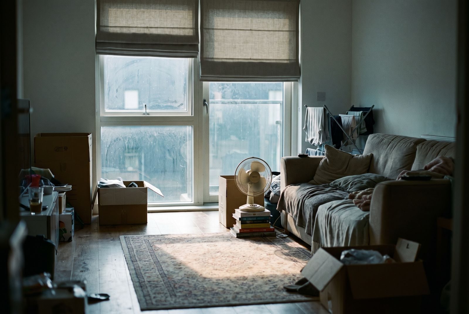 Sunlit new-build flat living room with a fan and half-drawn blinds