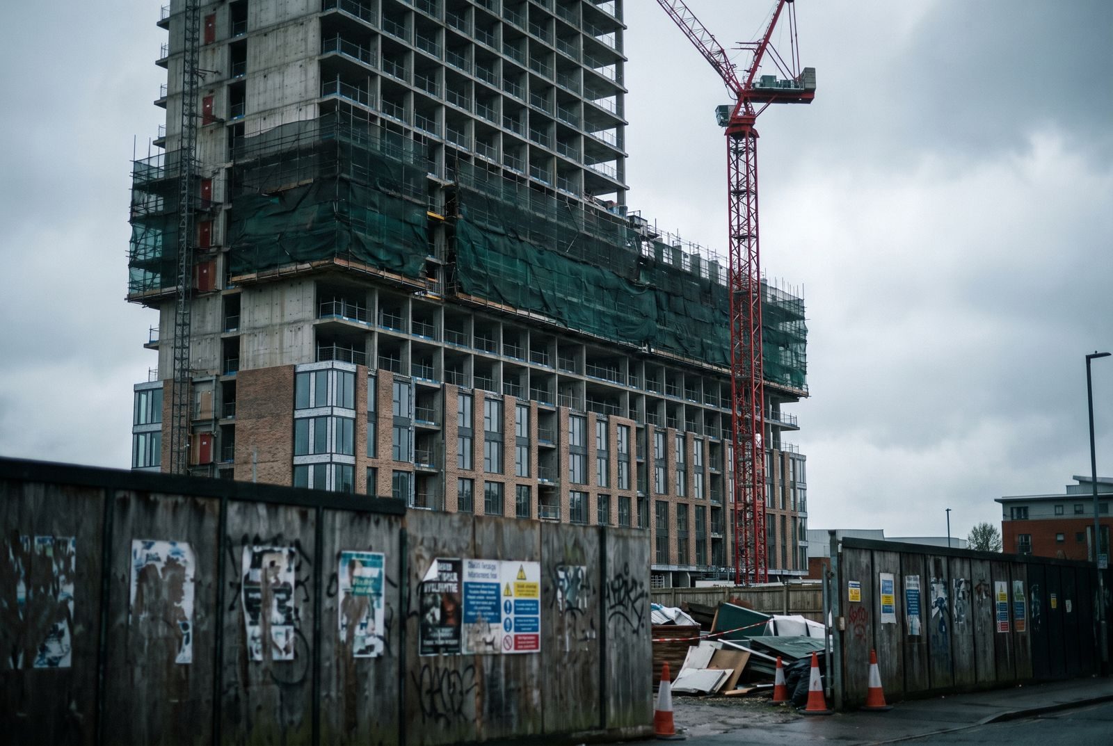 Residential tower under construction behind site hoarding